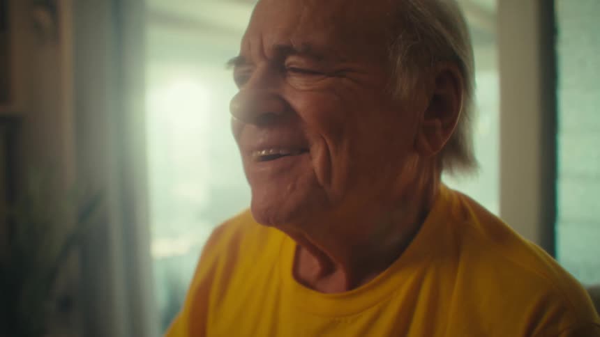 Elderly man smiles while looking to the side in a bright setting
