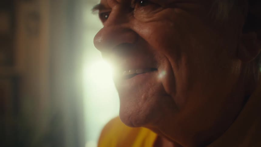 An elderly man stares looking forward and begins laughing