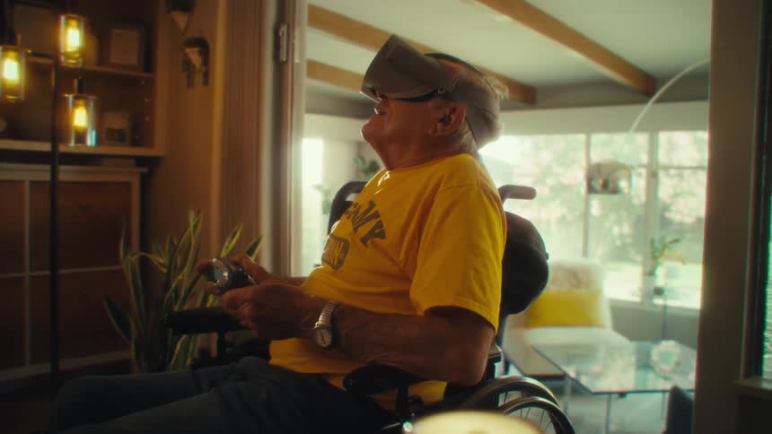 Man in a wheelchair uses virtual reality goggles while holding a controller