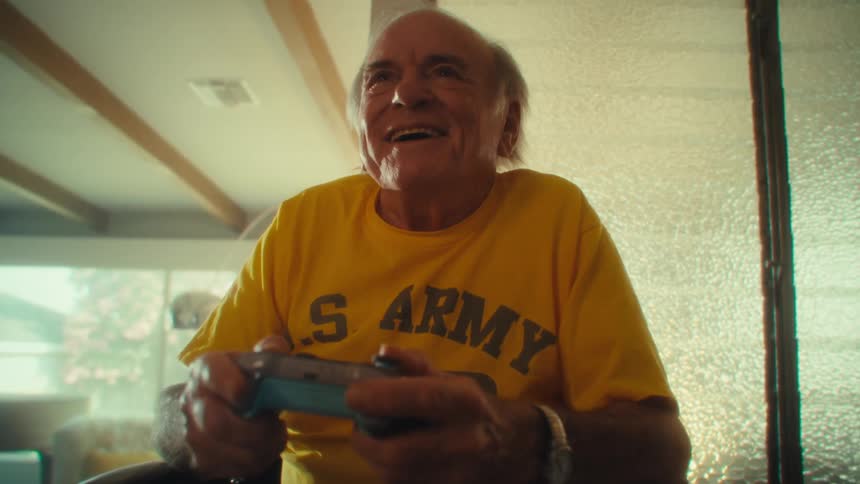 Elderly man in a wheelchair plays video games smiling with excitement