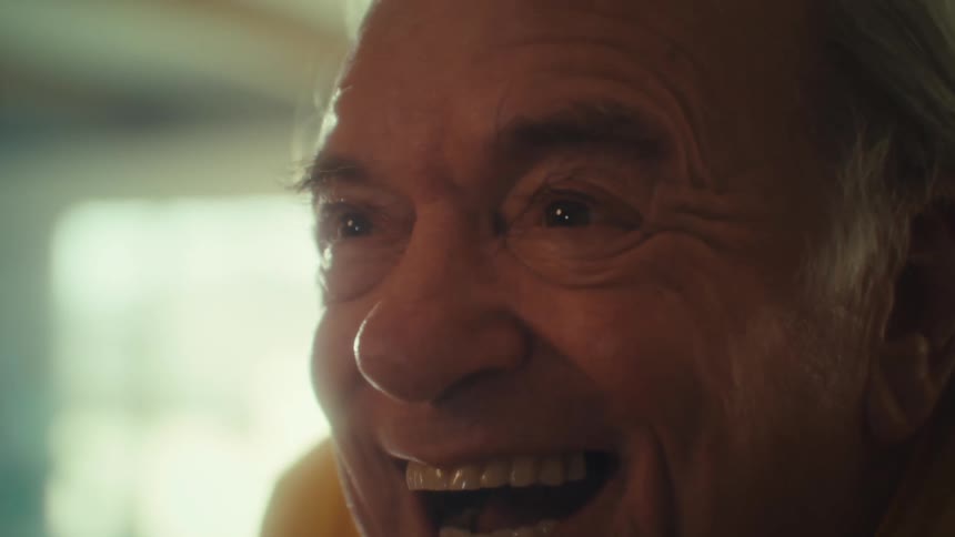 Elderly mans face appears in closeup smiling with excitement