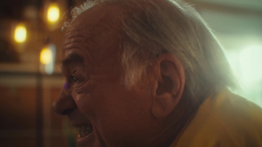 Man in a yellow shirt laughs with a joyful expression