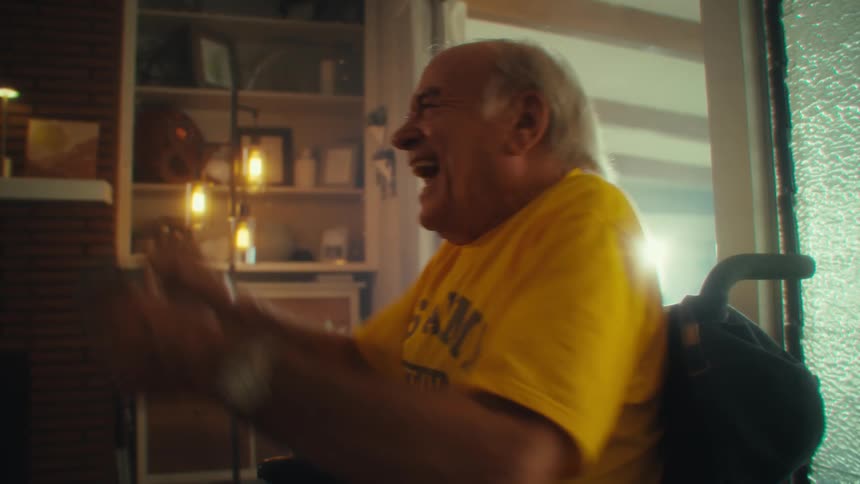 Elderly man happily video gaming indoors