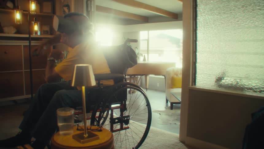 Man in a wheelchair wears virtual reality goggles while moving his arms playing