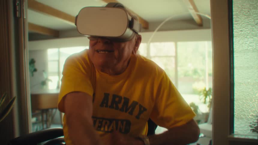 Elderly man enthusiastically interacts with vr headset while seated indoors