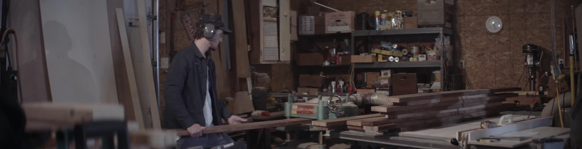 A man feeds a piece of lumber into a machine