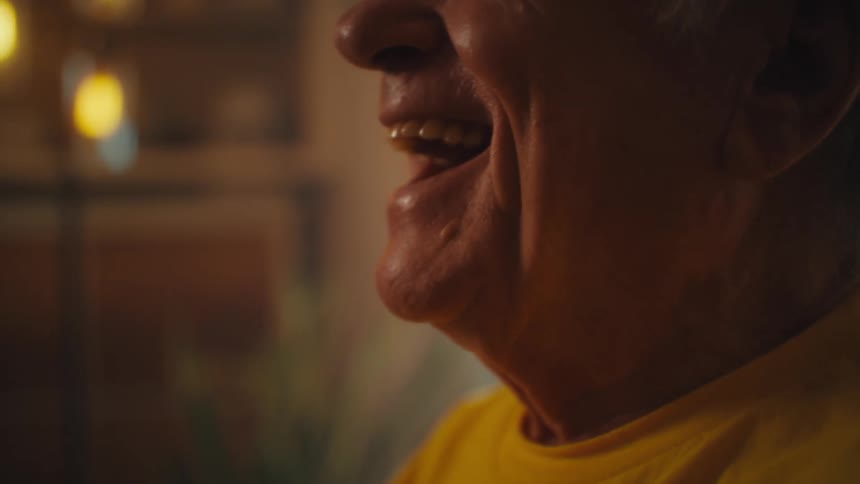 Elderly man holding and watching on a smiling cell phone
