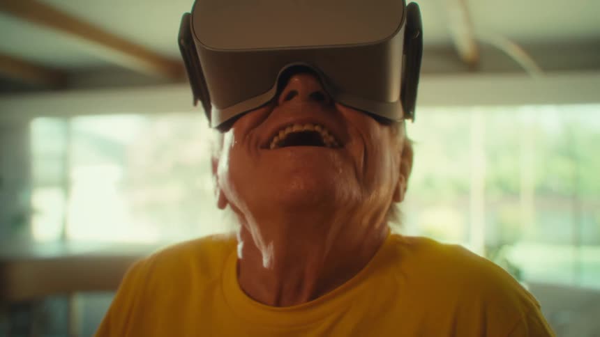 Smiling man in a yellow shirt wears virtual reality goggles
