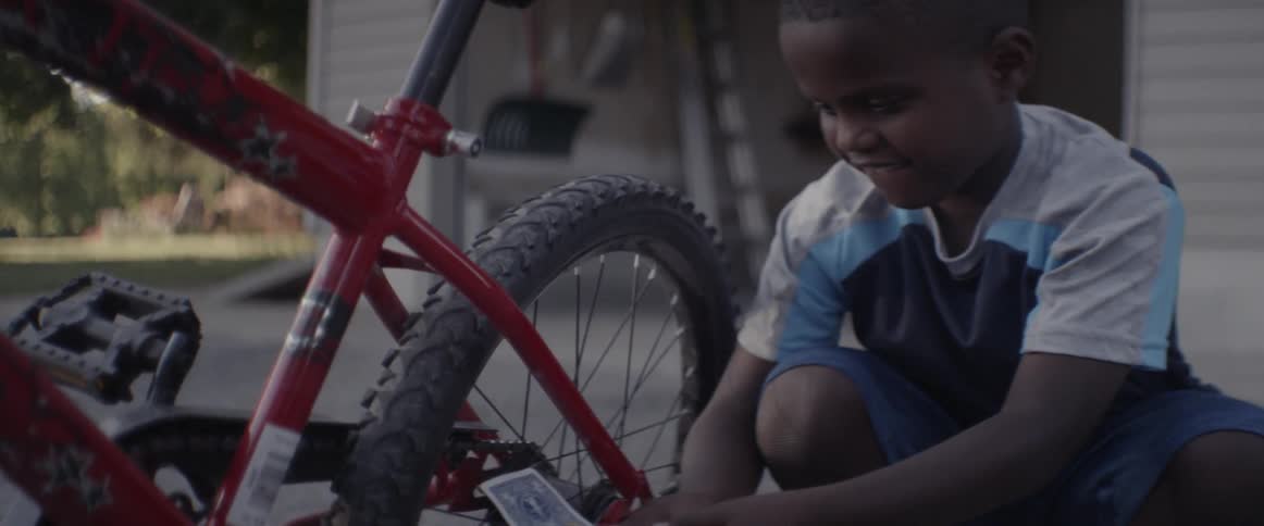 A boy attaches a playing card to his bike tire