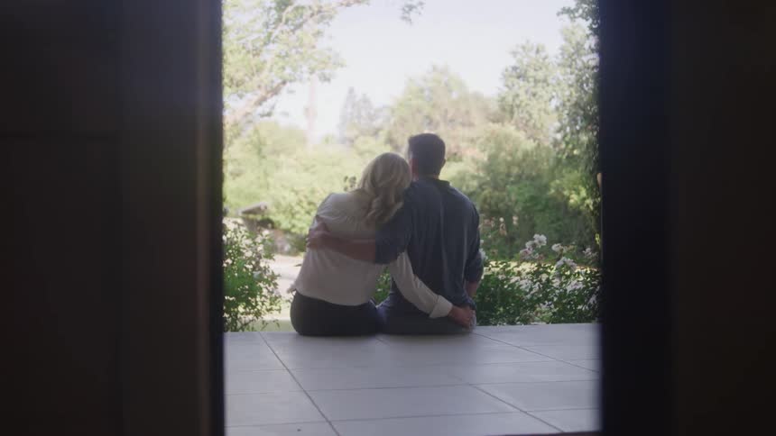 A couple hug on the porch through the doorway
