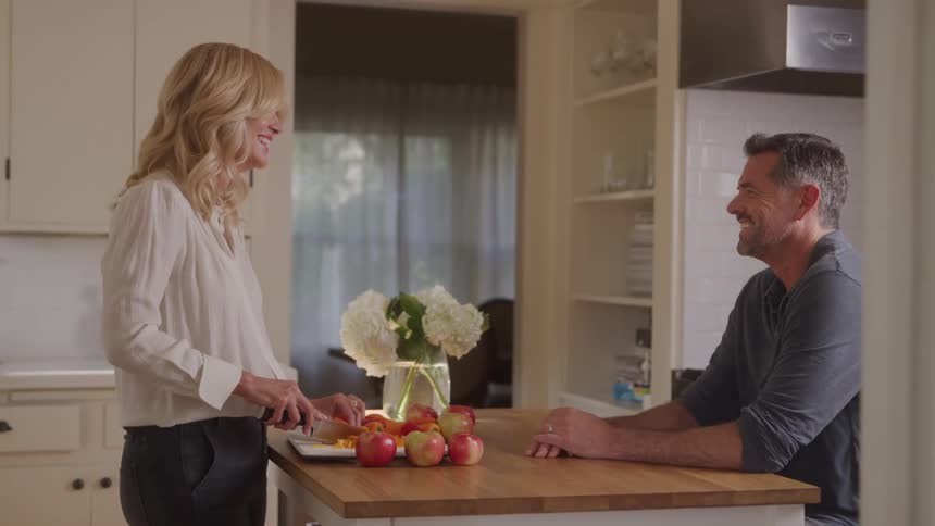 A man and woman walk while cutting apples