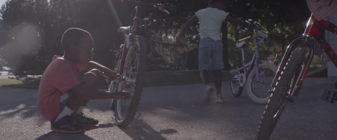 A boy uses a wrench on his bike tire