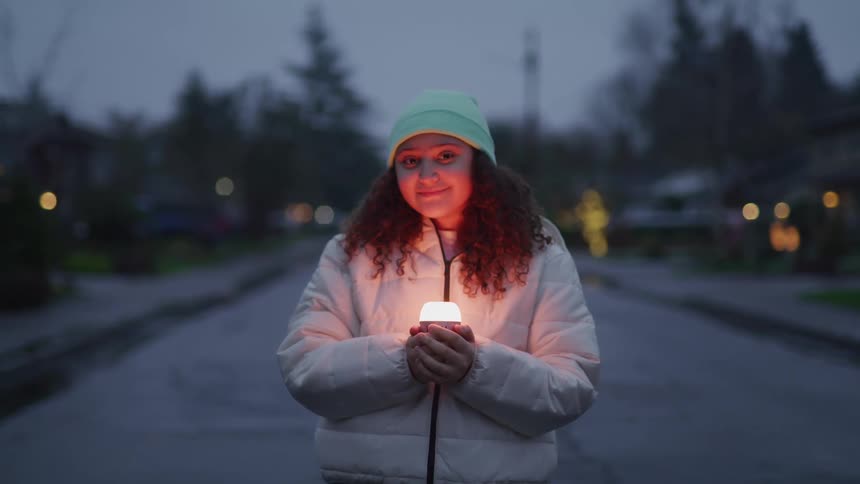 The girl smiles while holding a small light on the road