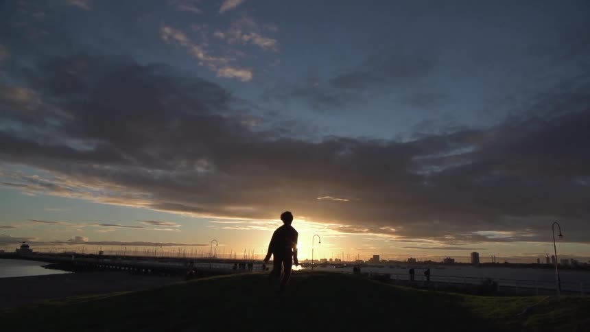 A person runs towards the setting sun