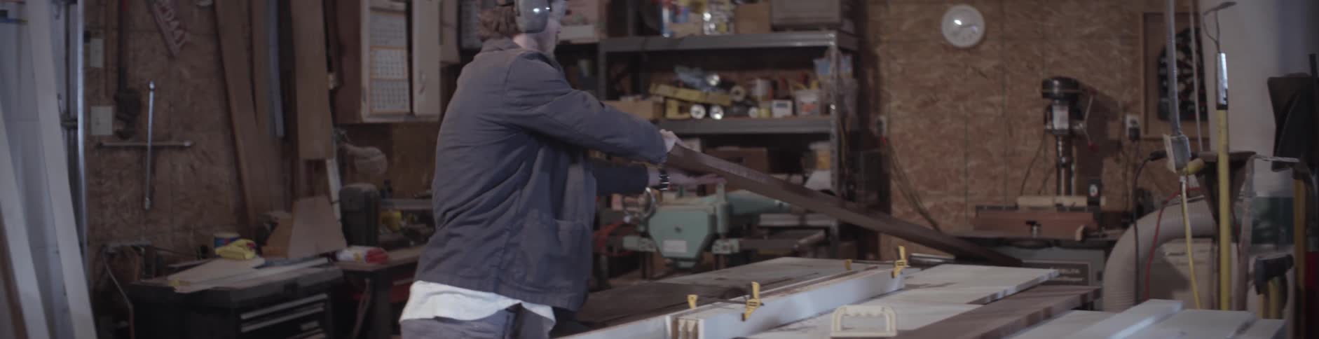 A man pushes a piece of wood into place on a table