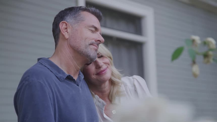 Woman rests her head on a mans shoulder while they smile serenely