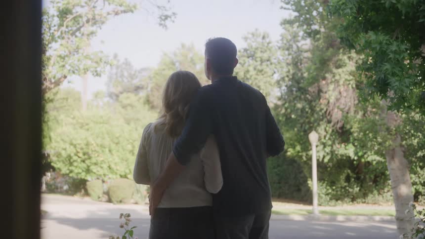 A loving middleaged couple with the mans arm around the woman in an outdoor setting surrounded by trees