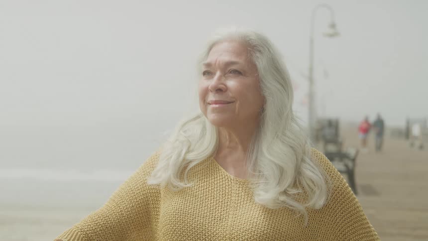 A woman is looking out at the water from the boardwalk