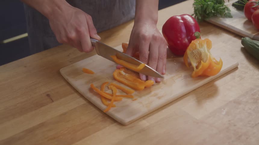 A woman is cutting peppers with a knife