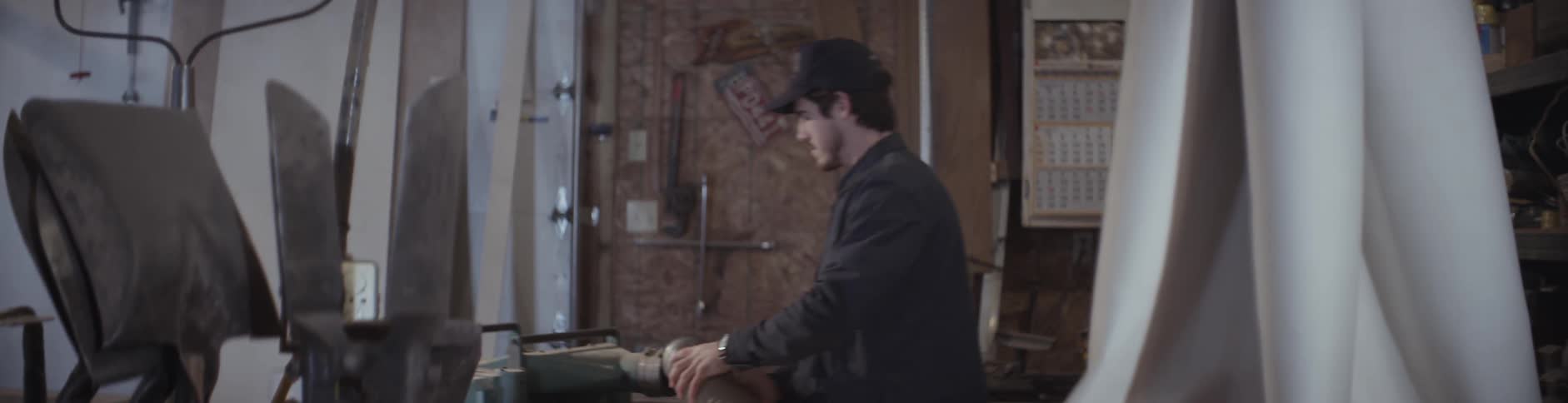 A man attaches a hose to a tool in a workshop