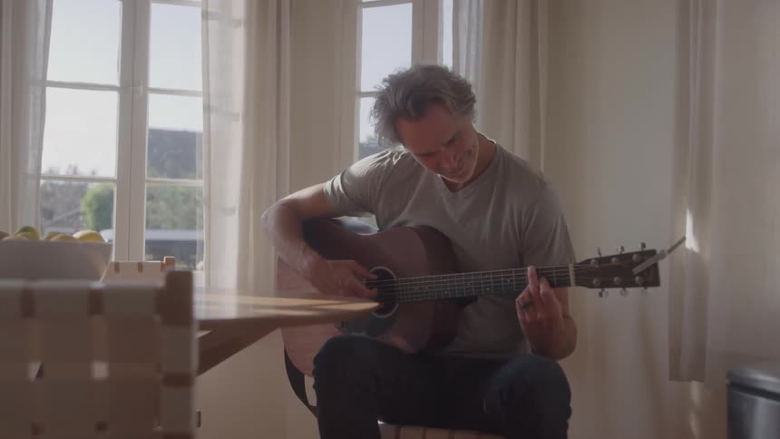 The man is playing the guitar at home