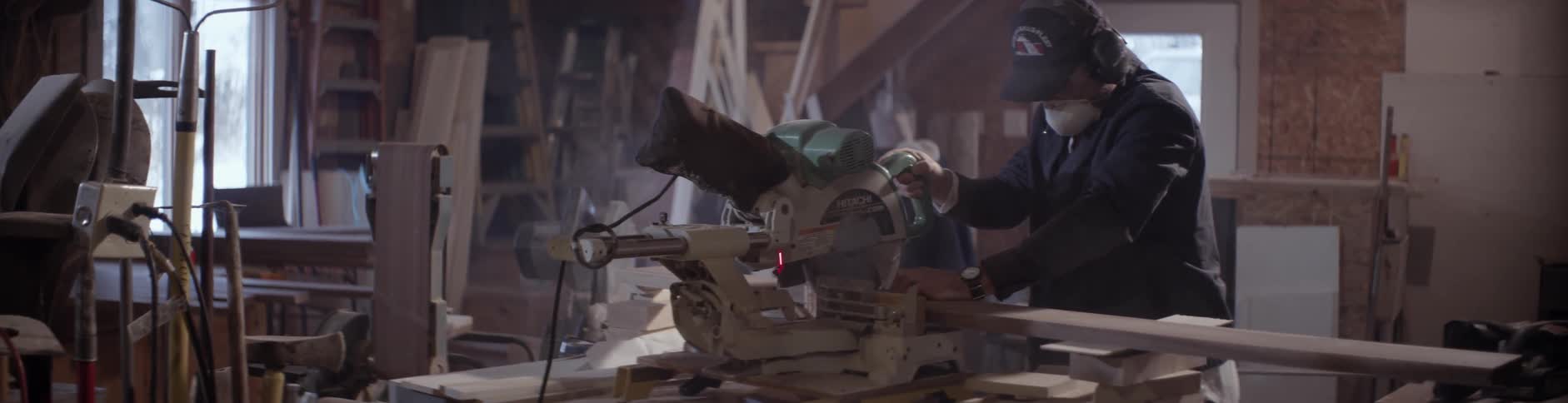 A man uses a table saw to cut lumber