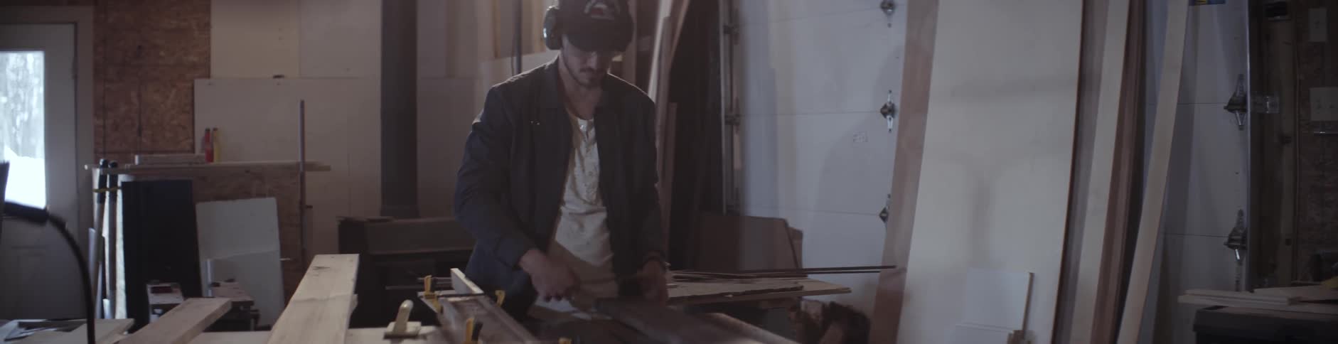 A man eyes a board on a workbench