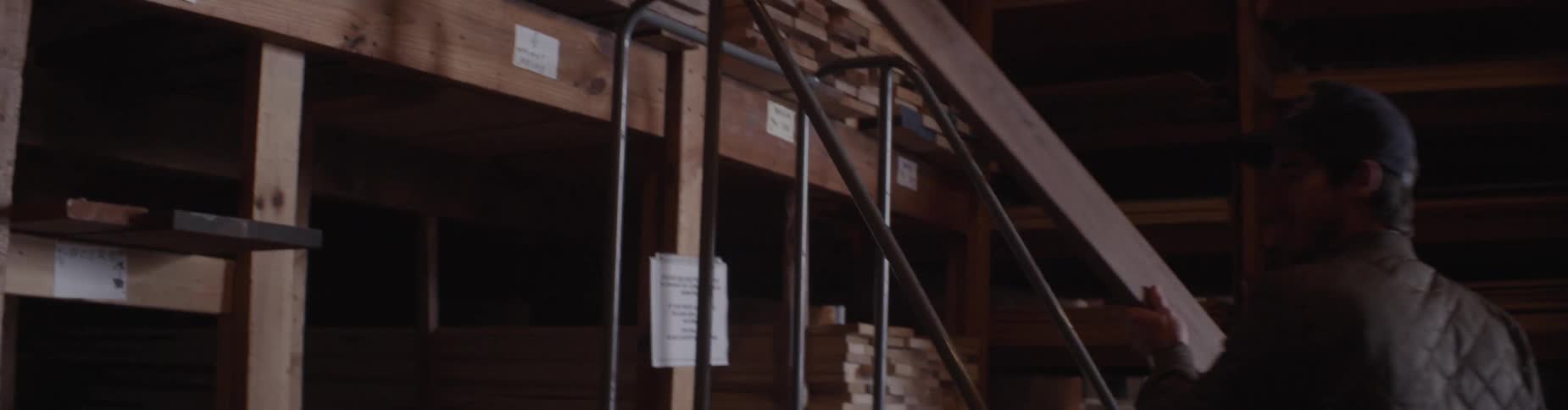 A man removes a piece of lumber from a shelf
