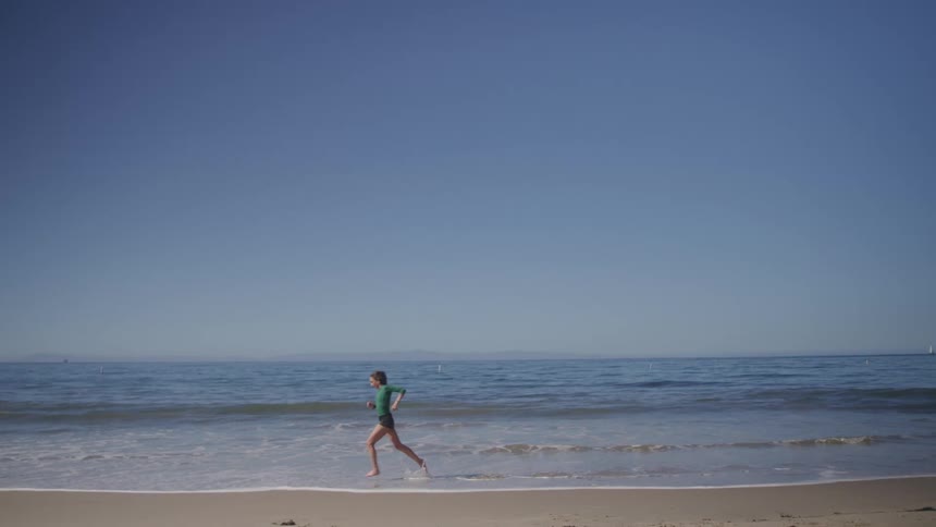 A person runs along the shoreline on a clear day
