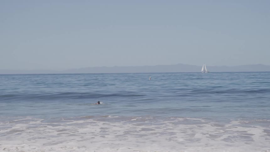 The man is swimming out into the ocean
