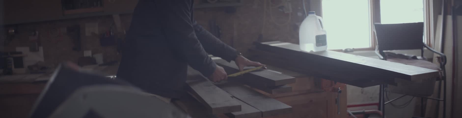 A man is measuring some pieces of wood