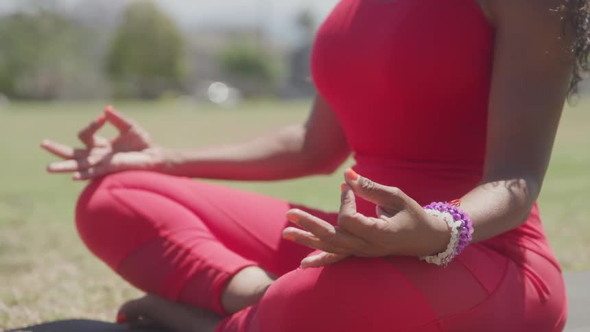 The woman is meditating on the grass