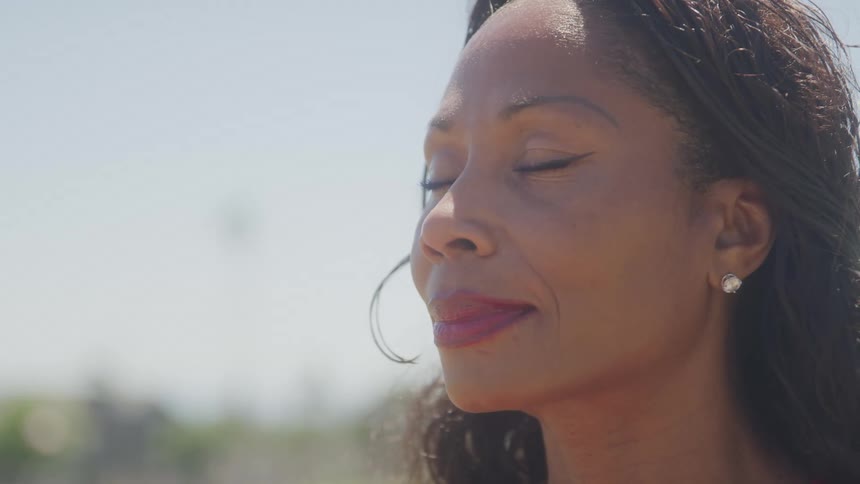 A woman wearing red lipstick practices yoga outdoors taking a deep breath at midday