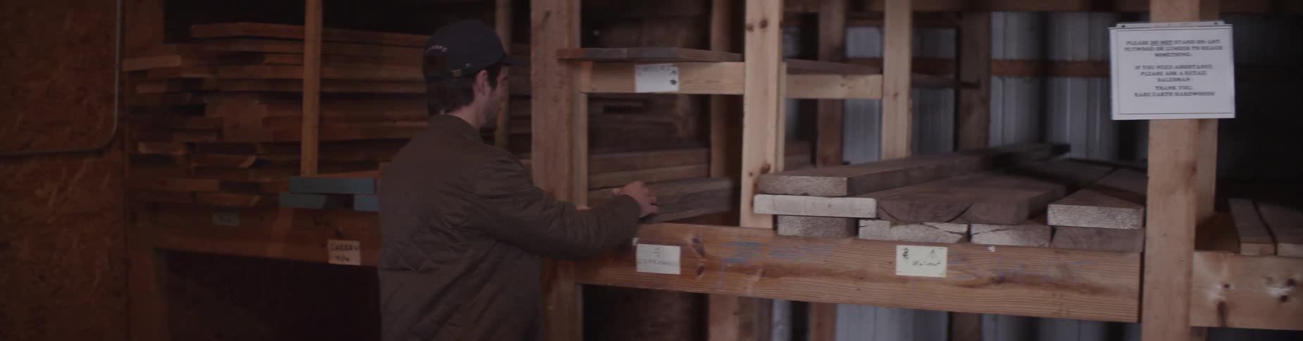 A man looks at lumber stacked on a shelf