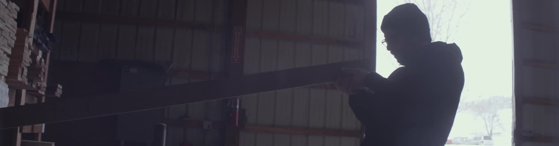 A man pulls a board from a warehouse shelf