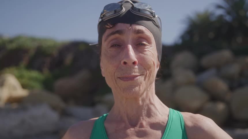 The woman earing a swimmers cap is smiling