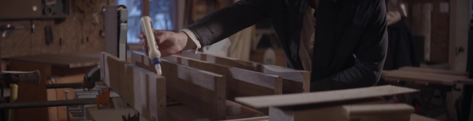 A man is putting glue on some boards