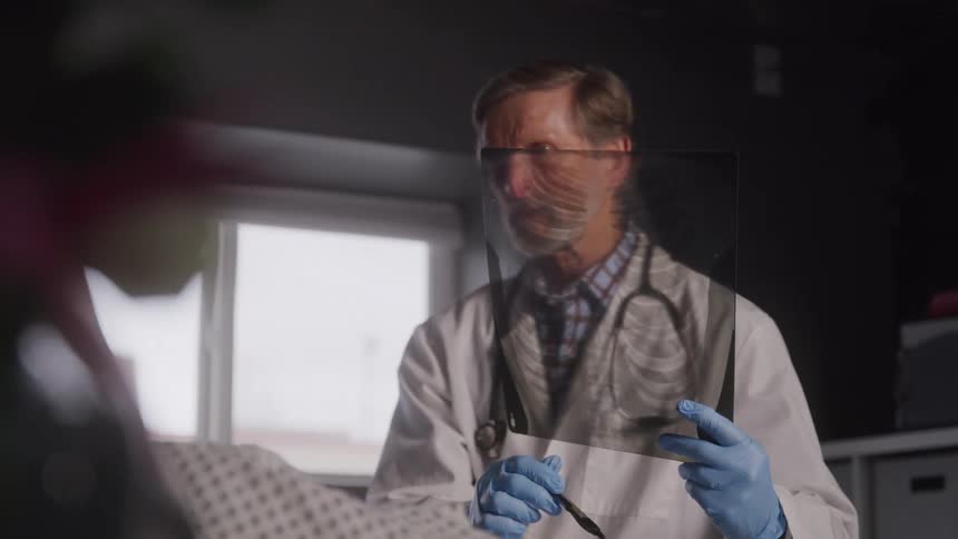 Male doctor in white coat examines xray in hospital