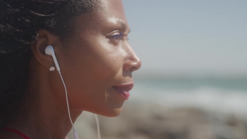 Woman enjoys music through headphones at beach