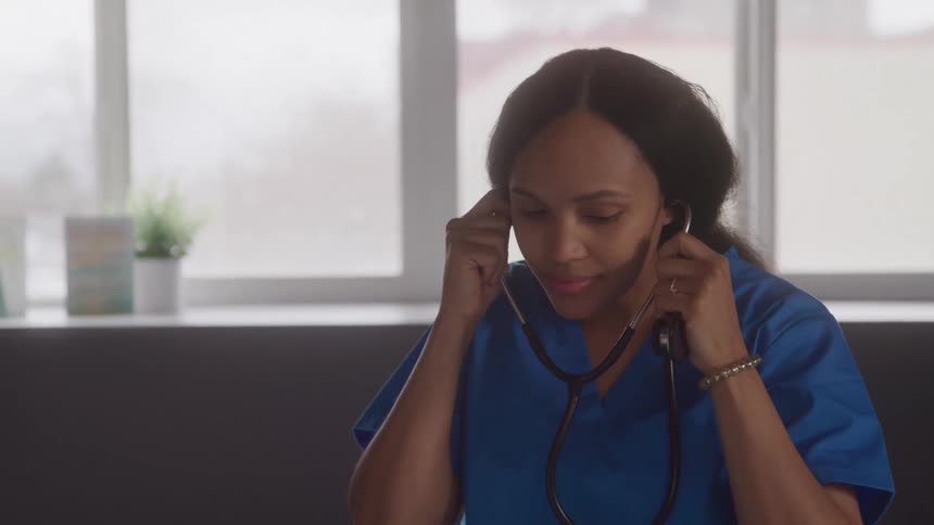 Woman in blue medical uniform puts a stethoscope in her ears