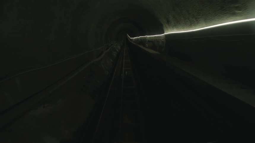 Traveling down a narrow dark tunnel with one string of light on the wall