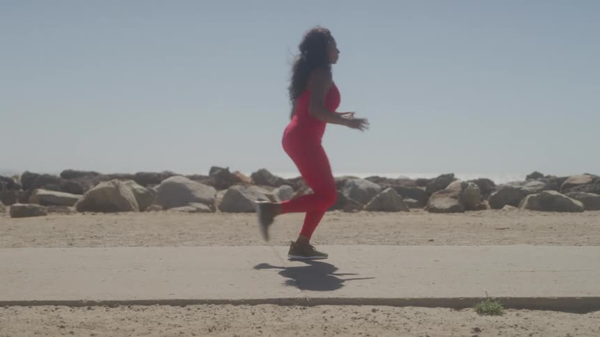 A young black woman runs outdoors along a pathway during daytime