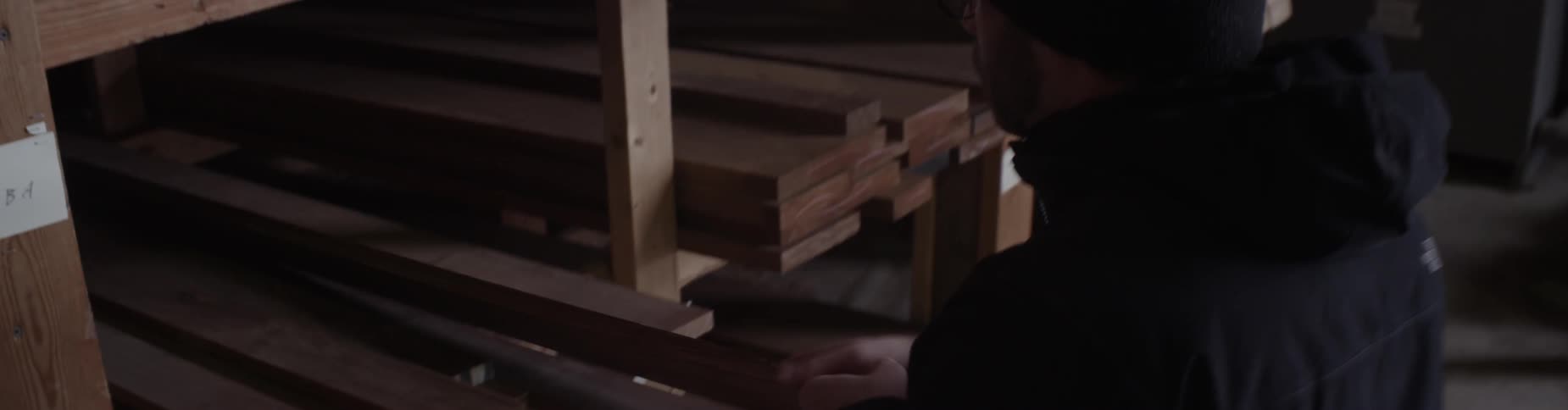 A man removes a piece of lumber from a shelf