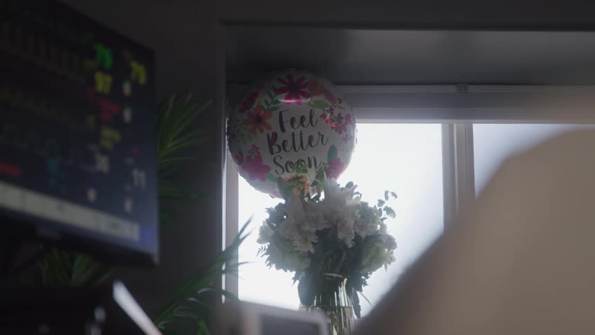 Bouquet of flowers and balloon sitting on window ledge in a hospital room
