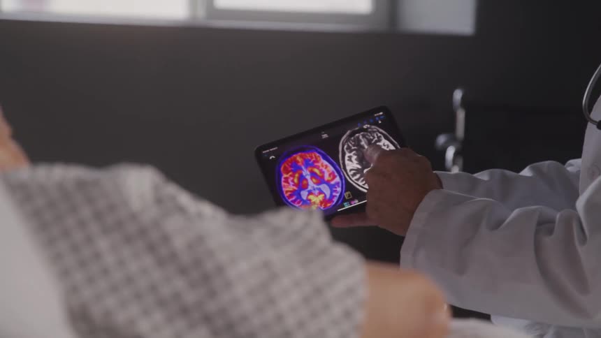 A doctor is showing a patient ct scans on a tablet