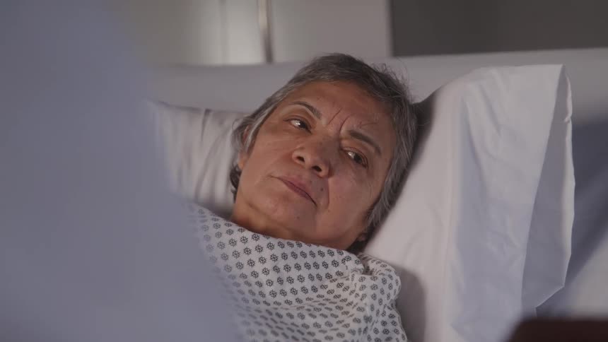 The woman is talking in her hospital bed
