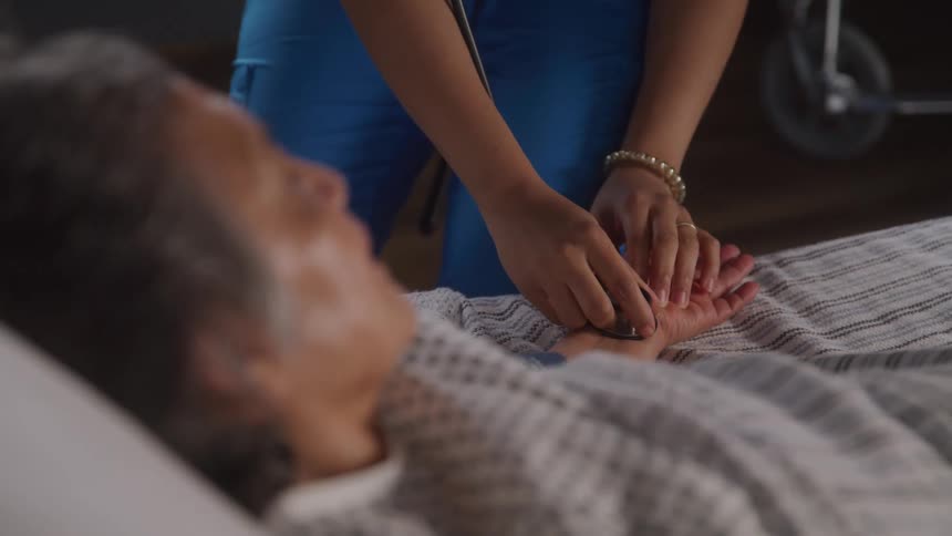 A nurse checks an elderly patient with a stethoscope with care