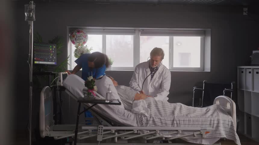 Doctor and nurse attending to a patient lying in a hospital bed