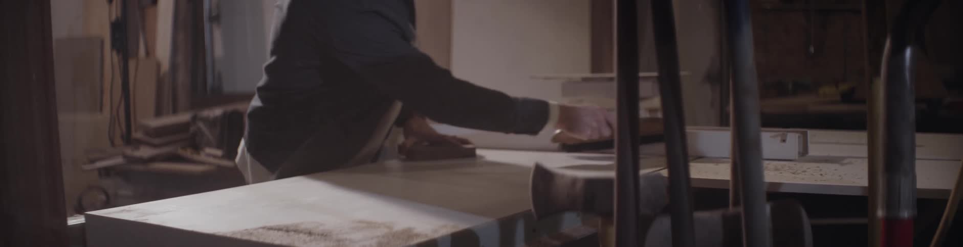 A man brushes sawdust off of a table