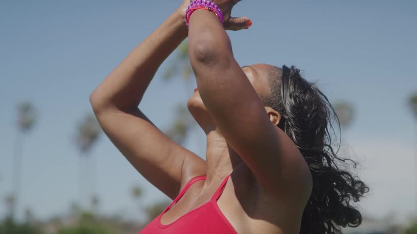 A woman wearing a red dress practices yoga outdoors under the sun